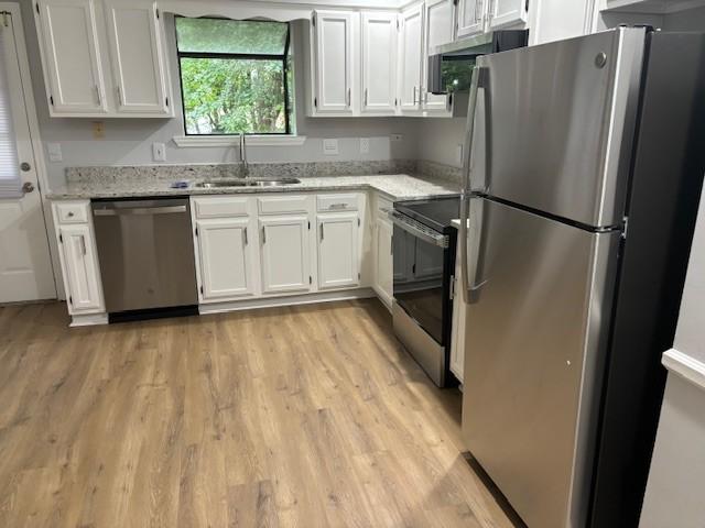 3332 Oak Trees Ct, Antioch, TN 37013 - kitchen with appliances with stainless steel finishes, light wood-style flooring, white cabinets, and light stone counters