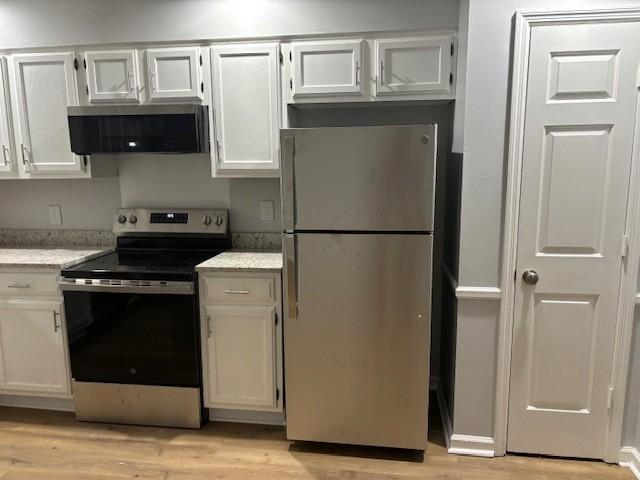 3332 Oak Trees Ct, Antioch, TN 37013 - kitchen featuring appliances with stainless steel finishes, light wood-style floors, ventilation hood, light stone counters, and white cabinets