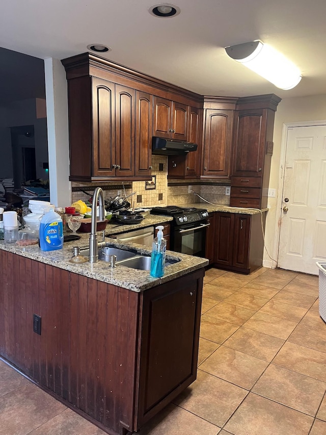 3412 Harborwood Cir, Nashville, TN 37214 - kitchen with black gas range oven, under cabinet range hood, backsplash, dark brown cabinetry, and light stone counters