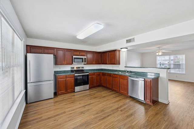 354 Arapaho Dr, Murfreesboro, TN 37128 - kitchen with appliances with stainless steel finishes, light wood-style flooring, dark countertops, a peninsula, and ceiling fan