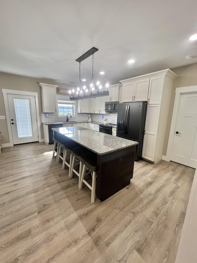 108 Chase Bend Rd, Estill Springs, TN 37330 - kitchen with black appliances, a center island, decorative backsplash, light wood-type flooring, and white cabinetry