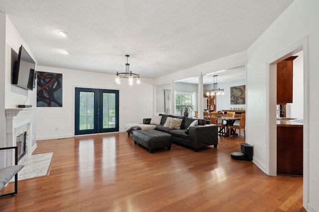 1908 Pointe Barton Dr, Lebanon, TN 37087 - living room with a chandelier, light wood-style floors, a fireplace, a textured ceiling, and french doors