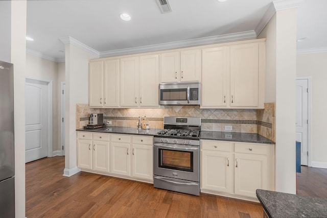 312 Rafferty Ct, Franklin, TN 37064 - kitchen with appliances with stainless steel finishes, cream cabinetry, ornamental molding, tasteful backsplash, and wood finished floors