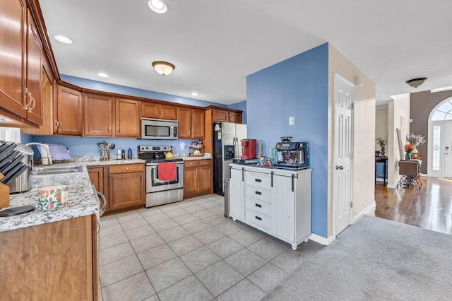 3299 Twelve Oaks Blvd, Clarksville, TN 37042 - kitchen featuring appliances with stainless steel finishes, brown cabinetry, light tile patterned flooring, recessed lighting, and light stone counters