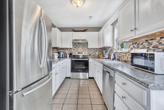 5601 Murphywood Xing, Antioch, TN 37013 - kitchen featuring stainless steel appliances, under cabinet range hood, light tile patterned flooring, white cabinetry, and tasteful backsplash