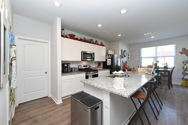 7050 Scotlyn Way, White House, TN 37188 - kitchen featuring stainless steel appliances, dark wood-style flooring, a breakfast bar area, white cabinetry, and recessed lighting
