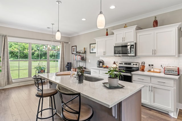1446 Millstone Creek Rd, Lascassas, TN 37085 - kitchen with appliances with stainless steel finishes, white cabinets, tasteful backsplash, an island with sink, and ornamental molding