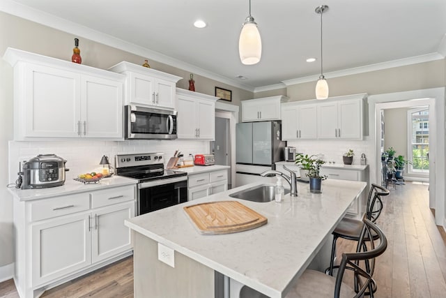 1446 Millstone Creek Rd, Lascassas, TN 37085 - kitchen featuring appliances with stainless steel finishes, a kitchen bar, white cabinetry, an island with sink, and crown molding
