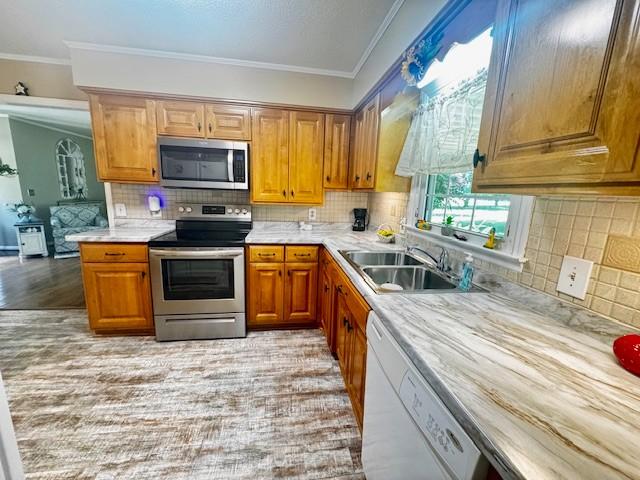 570 Gaines Cir, Estill Springs, TN 37330 - kitchen with appliances with stainless steel finishes, light countertops, ornamental molding, tasteful backsplash, and brown cabinetry