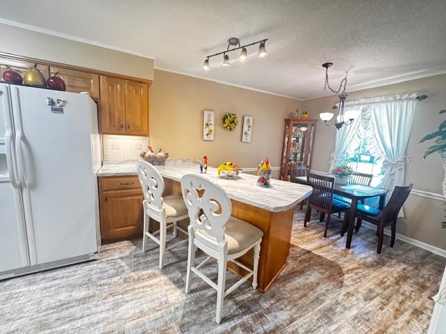 570 Gaines Cir, Estill Springs, TN 37330 - kitchen with white refrigerator with ice dispenser, a peninsula, brown cabinetry, light countertops, and ornamental molding