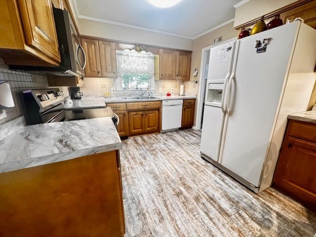 570 Gaines Cir, Estill Springs, TN 37330 - kitchen with white appliances, backsplash, brown cabinetry, light countertops, and crown molding