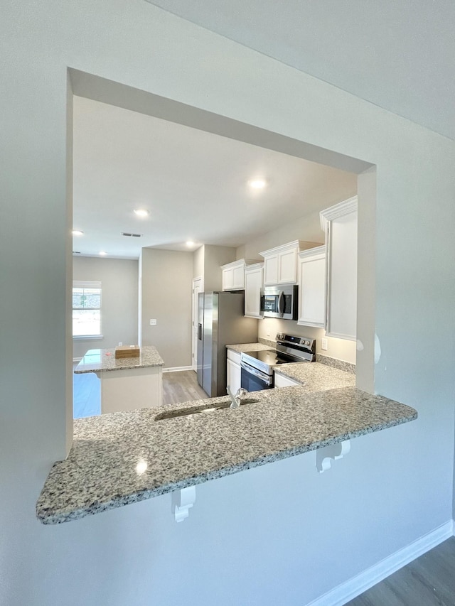404 Wren Way, Spring Hill, TN 37174 - kitchen with appliances with stainless steel finishes, light wood finished floors, light stone counters, a breakfast bar area, and recessed lighting