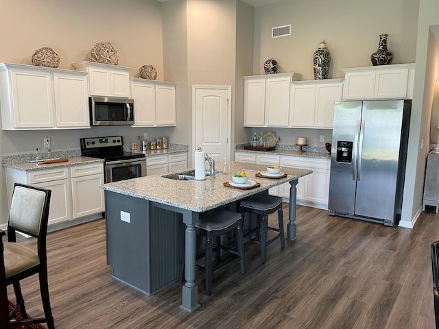 423 Wren Way, Spring Hill, TN 37174 - kitchen with stainless steel appliances, a towering ceiling, white cabinets, an island with sink, and a kitchen breakfast bar