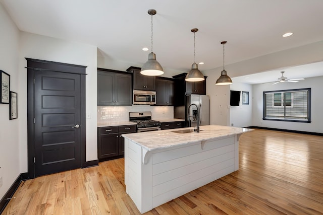 2136 Buena Vista Pike Unit B, Nashville, TN 37218 - kitchen featuring appliances with stainless steel finishes, light wood finished floors, tasteful backsplash, an island with sink, and ceiling fan