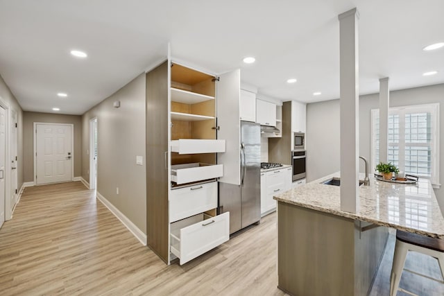 438 Siena Dr, Nashville, TN 37205 - kitchen featuring stainless steel appliances, white cabinetry, light wood finished floors, under cabinet range hood, and light stone counters
