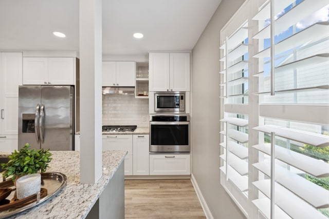 438 Siena Dr, Nashville, TN 37205 - kitchen with appliances with stainless steel finishes, under cabinet range hood, light wood-type flooring, decorative backsplash, and white cabinetry