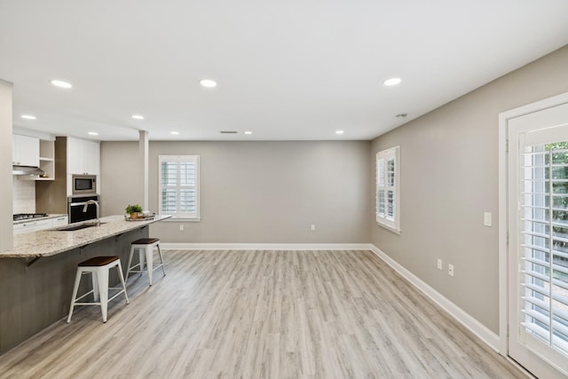438 Siena Dr, Nashville, TN 37205 - kitchen featuring stainless steel appliances, white cabinets, a kitchen bar, light wood-style flooring, and recessed lighting