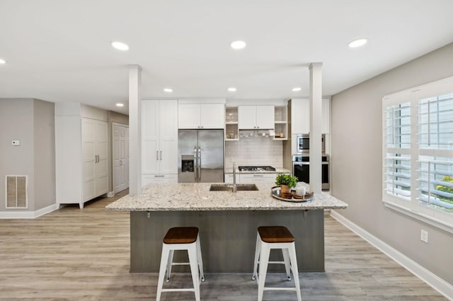 438 Siena Dr, Nashville, TN 37205 - kitchen with appliances with stainless steel finishes, white cabinetry, a breakfast bar, light wood-style floors, and recessed lighting