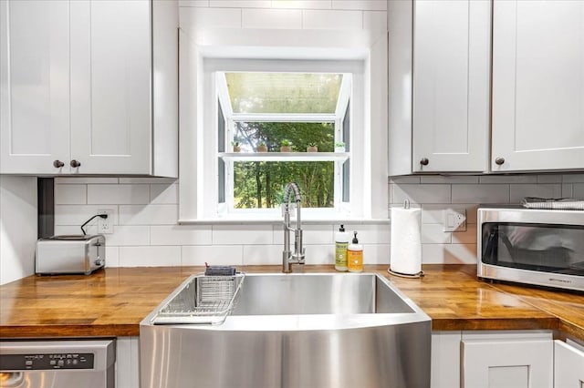 802 Evans Rd, Winchester, TN 37398 - kitchen featuring butcher block counters, stainless steel microwave, dishwasher, and decorative backsplash