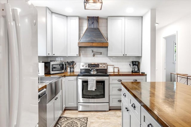 802 Evans Rd, Winchester, TN 37398 - kitchen featuring butcher block counters, wall chimney range hood, appliances with stainless steel finishes, decorative backsplash, and recessed lighting
