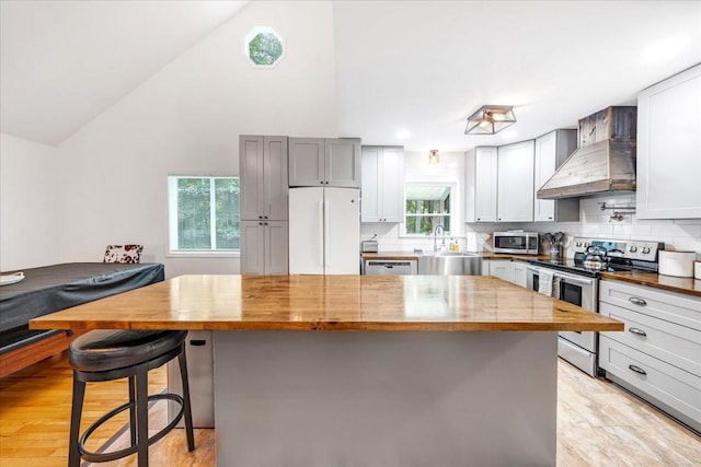 802 Evans Rd, Winchester, TN 37398 - kitchen featuring stainless steel appliances, wall chimney exhaust hood, wooden counters, light wood finished floors, and a kitchen bar