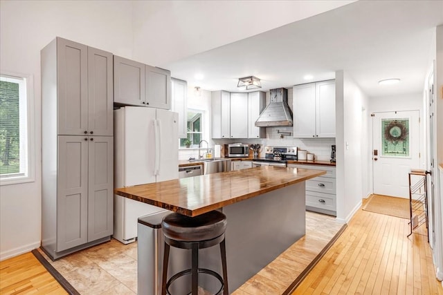 802 Evans Rd, Winchester, TN 37398 - kitchen featuring wood counters, wall chimney exhaust hood, appliances with stainless steel finishes, light wood-style floors, and backsplash