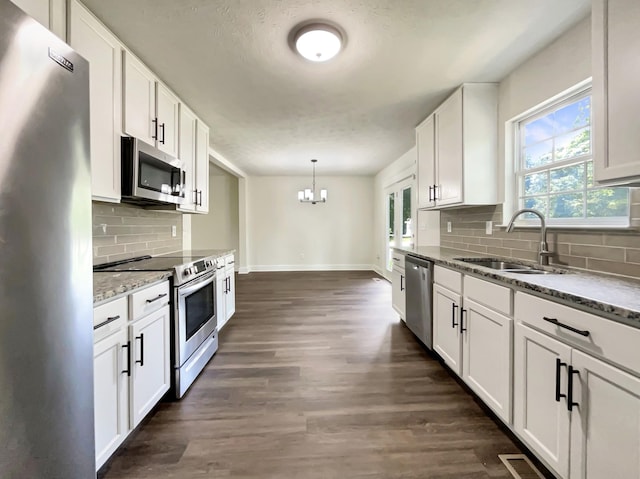 7203 Chester Rd, Fairview, TN 37062 - kitchen with appliances with stainless steel finishes, a chandelier, light stone countertops, and dark wood-style flooring