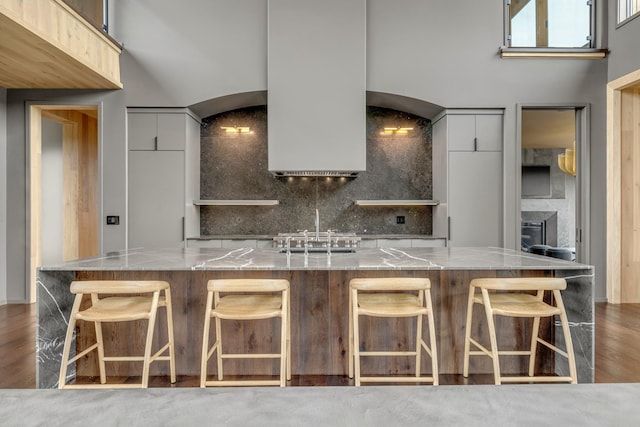 8005 Backwoods Dr, College Grove, TN 37046 - kitchen featuring modern cabinets, tasteful backsplash, light stone counters, a spacious island, and a breakfast bar area