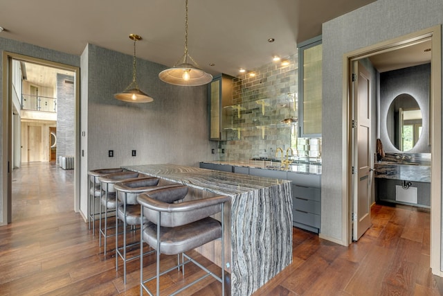 8005 Backwoods Dr, College Grove, TN 37046 - kitchen with dark wood finished floors, light stone countertops, hanging light fixtures, and a kitchen bar