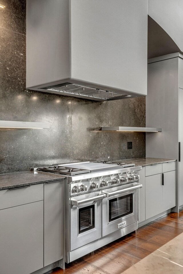 8005 Backwoods Dr, College Grove, TN 37046 - kitchen with double oven range, wall chimney exhaust hood, white cabinets, backsplash, and wood finished floors