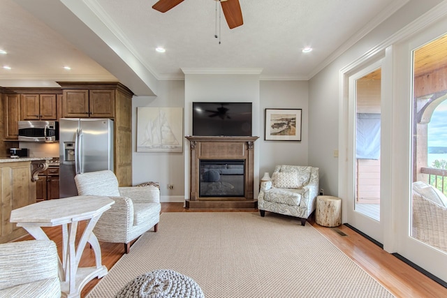55B Oasis Ln, Savannah, TN 38372 - living area with light wood-style floors, a glass covered fireplace, crown molding, ceiling fan, and recessed lighting