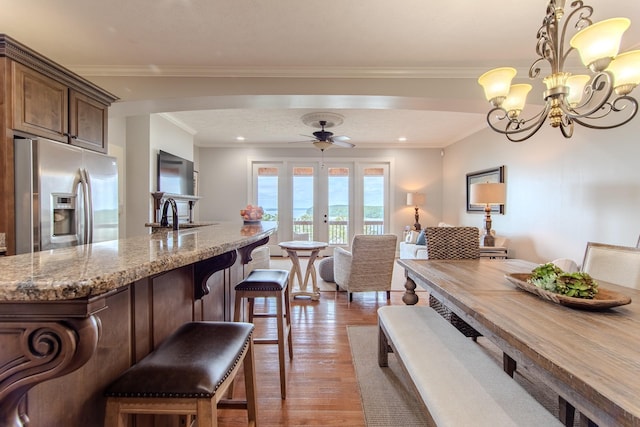 55B Oasis Ln, Savannah, TN 38372 - kitchen featuring stainless steel fridge with ice dispenser, a breakfast bar area, light stone counters, arched walkways, and light wood-style floors
