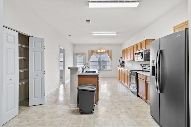 219 Wyndom Ct, Goodlettsville, TN 37072 - kitchen with appliances with stainless steel finishes, a chandelier, light countertops, a kitchen island with sink, and brown cabinets