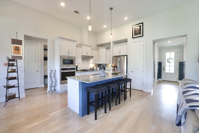 511 Oakvale Ln, Mount Juliet, TN 37122 - kitchen with stainless steel appliances, white cabinets, under cabinet range hood, a breakfast bar, and light wood finished floors