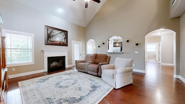 1007 Via Francesco Way, Spring Hill, TN 37174 - living room featuring a ceiling fan, dark wood-style floors, a fireplace with raised hearth, high vaulted ceiling, and arched walkways