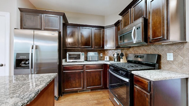 1007 Via Francesco Way, Spring Hill, TN 37174 - kitchen with appliances with stainless steel finishes, light stone counters, dark brown cabinets, and decorative backsplash