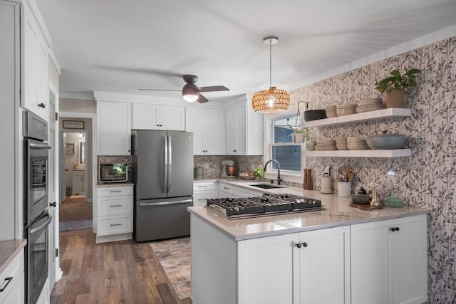 1400 Manor Rd, Columbia, TN 38401 - kitchen with appliances with stainless steel finishes, a peninsula, wood finished floors, white cabinets, and decorative backsplash