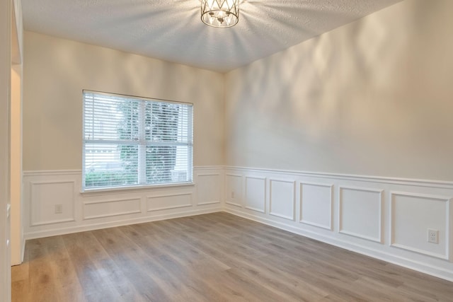 317 Sarava Ln, Smyrna, TN 37167 - unfurnished room featuring light wood-type flooring, wainscoting, a decorative wall, and a textured ceiling