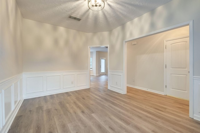 317 Sarava Ln, Smyrna, TN 37167 - unfurnished room with light wood finished floors, a wainscoted wall, a decorative wall, and a textured ceiling