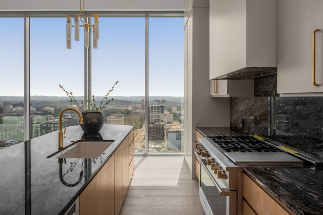 1616 W End Ave Unit 3304, Nashville, TN 37203 - kitchen featuring high end white range oven, light wood finished floors, dark stone counters, backsplash, and wall chimney exhaust hood