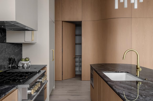 1616 W End Ave Unit 3304, Nashville, TN 37203 - kitchen featuring stainless steel gas range oven, range hood, dark stone counters, light wood-type flooring, and tasteful backsplash