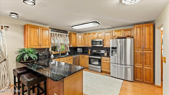 573 Hilltop Dr, Jacksboro, TN 37757 - kitchen with stainless steel appliances, a peninsula, tasteful backsplash, light wood-style floors, and a kitchen bar