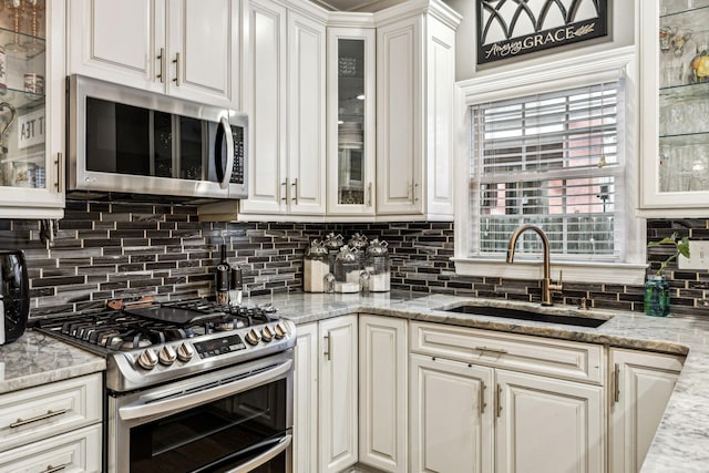 314 W 6th St, Columbia, TN 38401 - kitchen featuring appliances with stainless steel finishes, white cabinetry, tasteful backsplash, light stone counters, and glass insert cabinets