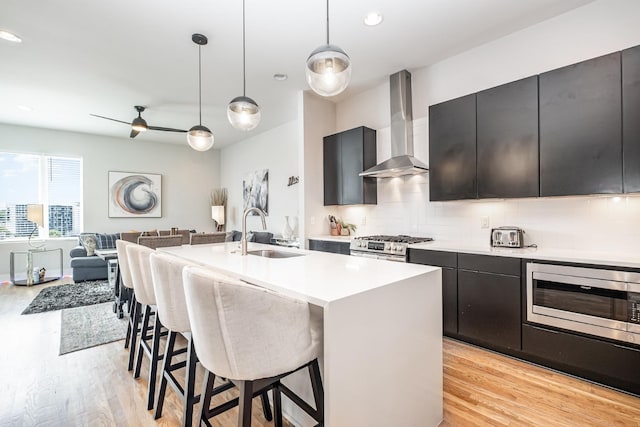 2910 Felicia St Unit 1, Nashville, TN 37209 - kitchen featuring wall chimney exhaust hood, appliances with stainless steel finishes, light wood finished floors, a kitchen breakfast bar, and recessed lighting