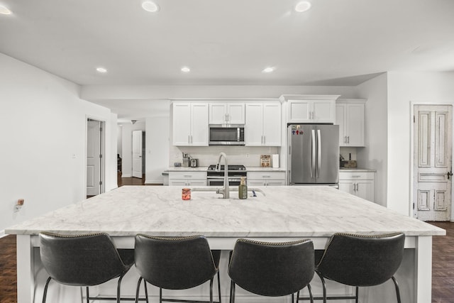 516 Delacy Dr, Fairview, TN 37062 - kitchen featuring stainless steel appliances, a center island with sink, white cabinetry, a breakfast bar area, and recessed lighting