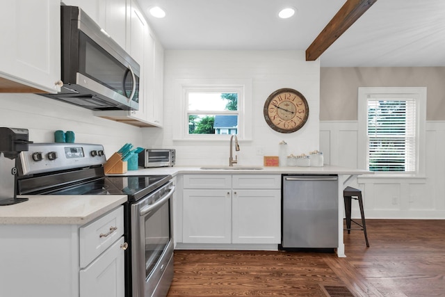 1803 Dimple Ct, Columbia, TN 38401 - kitchen featuring stainless steel appliances, white cabinetry, dark wood finished floors, beamed ceiling, and a wainscoted wall