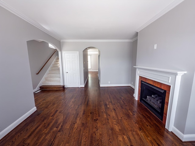 527 32nd Ave S, Nashville, TN 37212 - unfurnished living room featuring a tiled fireplace, dark wood-type flooring, ornamental molding, and arched walkways