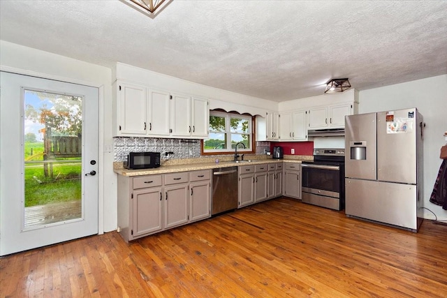 135 Campbellsville Pike, Ethridge, TN 38456 - kitchen with appliances with stainless steel finishes, under cabinet range hood, hardwood / wood-style flooring, light countertops, and a textured ceiling