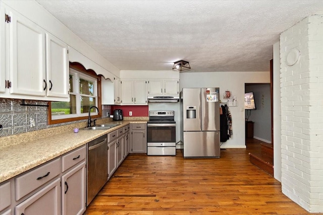 135 Campbellsville Pike, Ethridge, TN 38456 - kitchen featuring appliances with stainless steel finishes, under cabinet range hood, wood finished floors, a textured ceiling, and light countertops