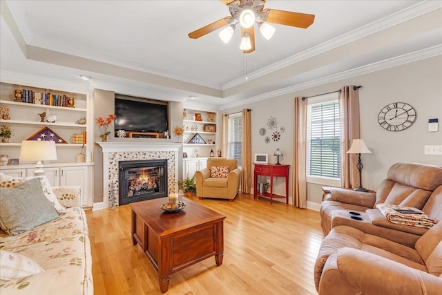 379 Hooper Rd, Winchester, TN 37398 - living area featuring a ceiling fan, light wood-type flooring, a tiled fireplace, a raised ceiling, and ornamental molding